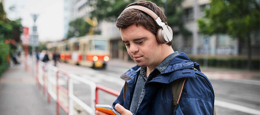 man at bus stop with headphones and holding phone