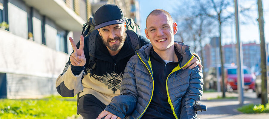 Caregiver walking outside with a young man in a wheelchair