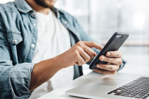 Man at computer and using his mobile device