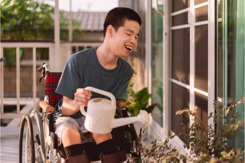 young man in wheelchair watering a garden