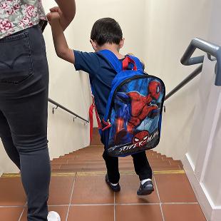 child holding adults hand walking down stairs