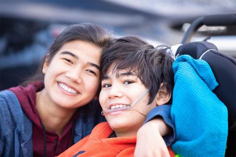 Woman smiling with boy that is also smiling in wheelchair.